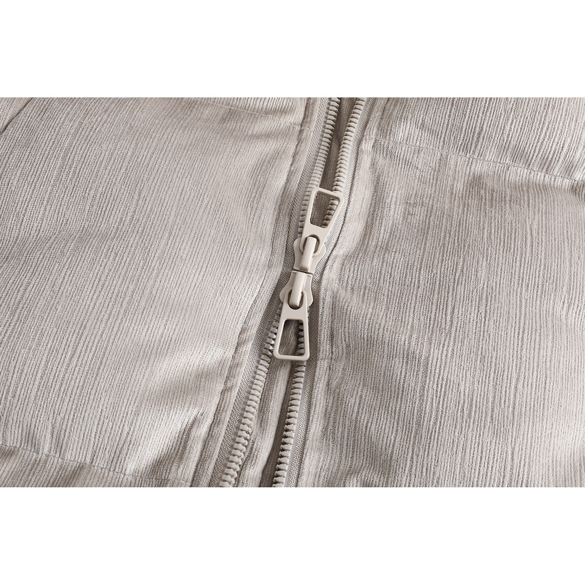 Close-up of the light taupe jacket's double zipper and fine ribbed fabric texture.
