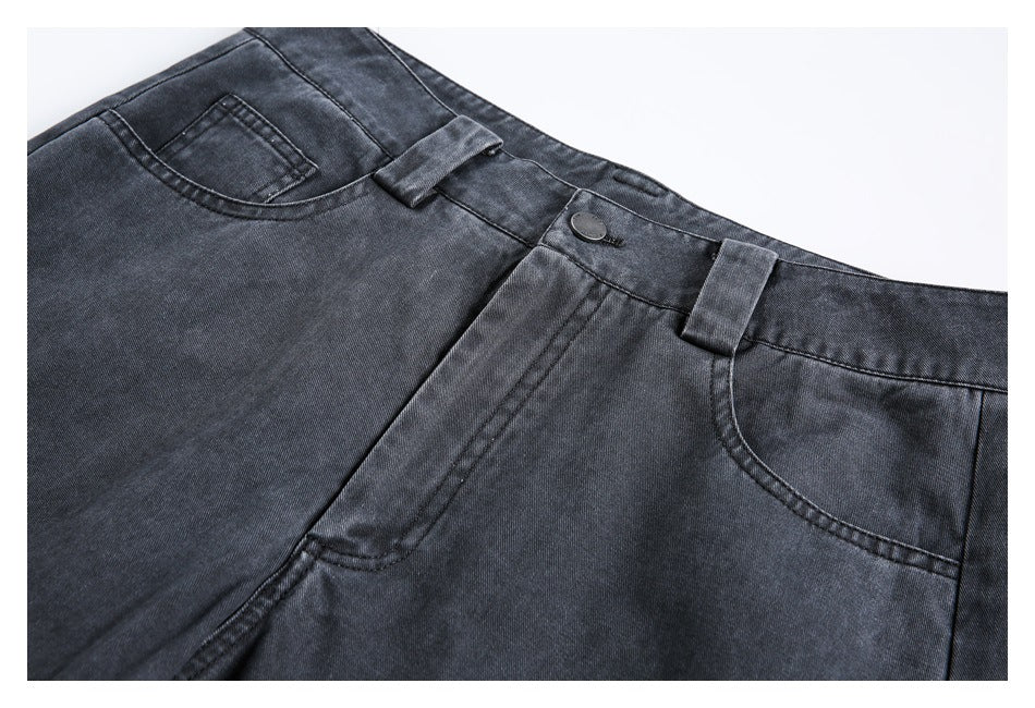Close-up of dark charcoal jeans showing the waistband, button, belt loops, fly and front pockets.