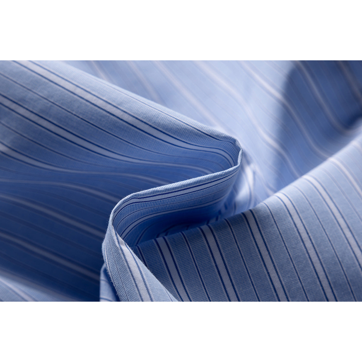 Macro view of light blue fabric with narrow dark blue stripes and a folded, stitched edge.