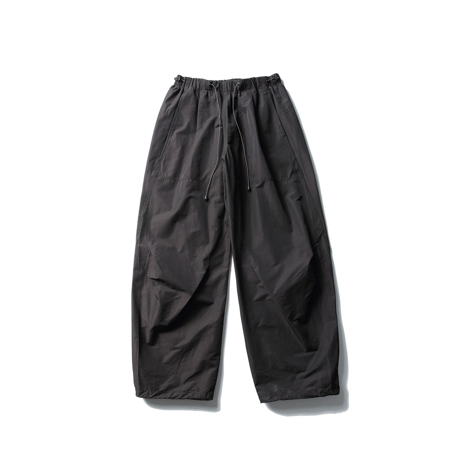 Black wide-leg parachute pants with drawcord elastic waistband, flat lay front view