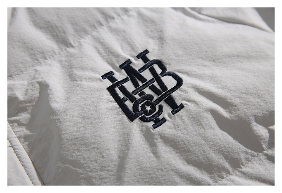 Close-up of a dark embroidered emblem on the light-colored jacket.