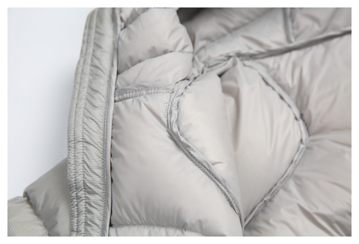 Close-up of padded light gray jacket panels and curved stitched seams beside the striped outer edge.