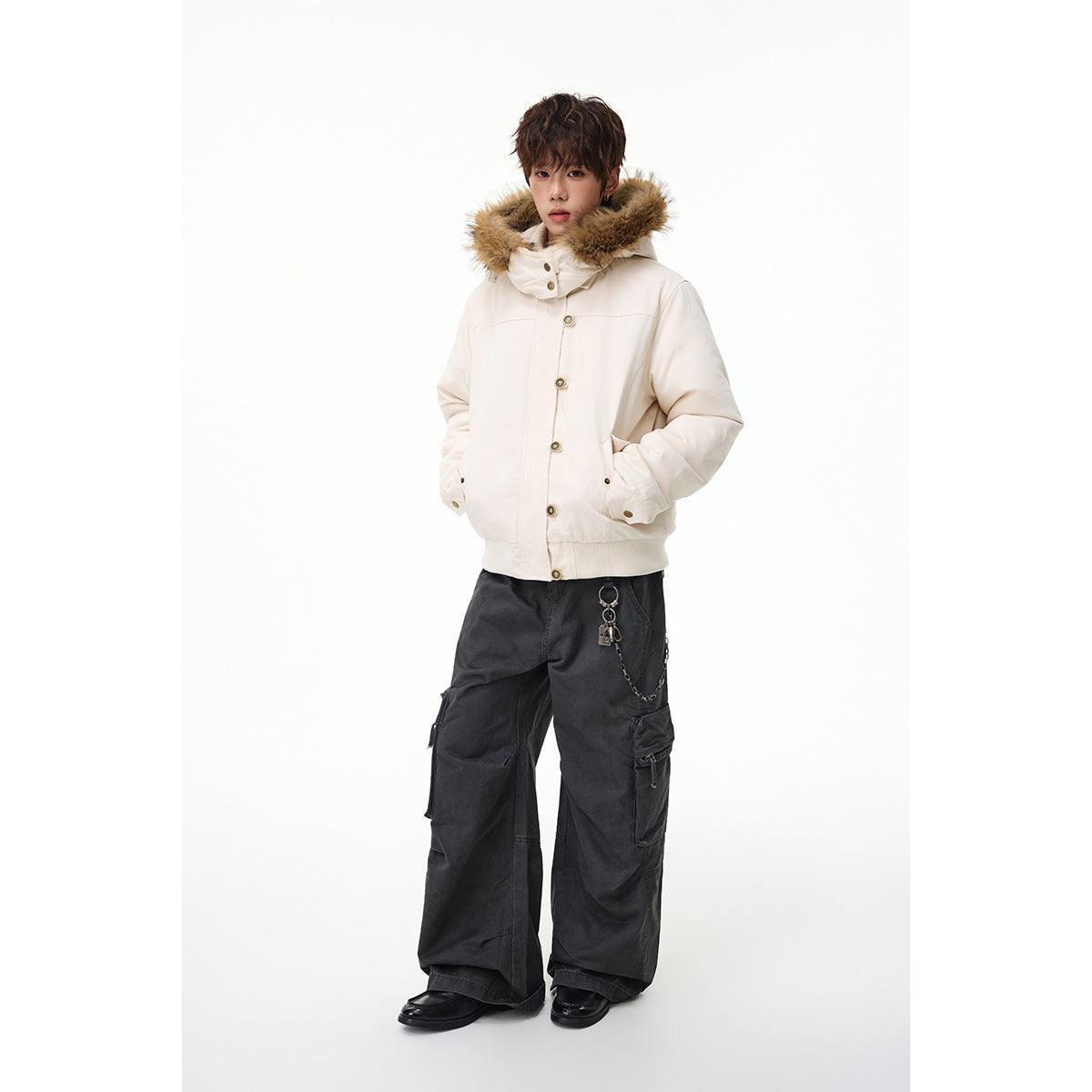 Model wearing an ivory hooded jacket with tan fur trim and button front, styled with dark cargo pants.