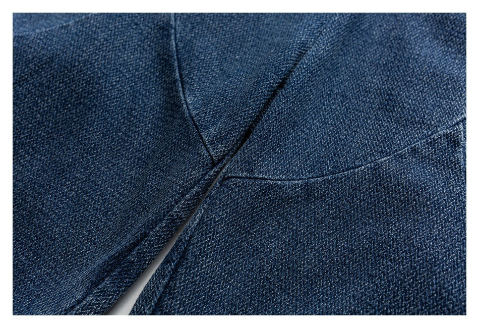 Macro view of dark blue denim trouser fabric and intersecting stitched seams.