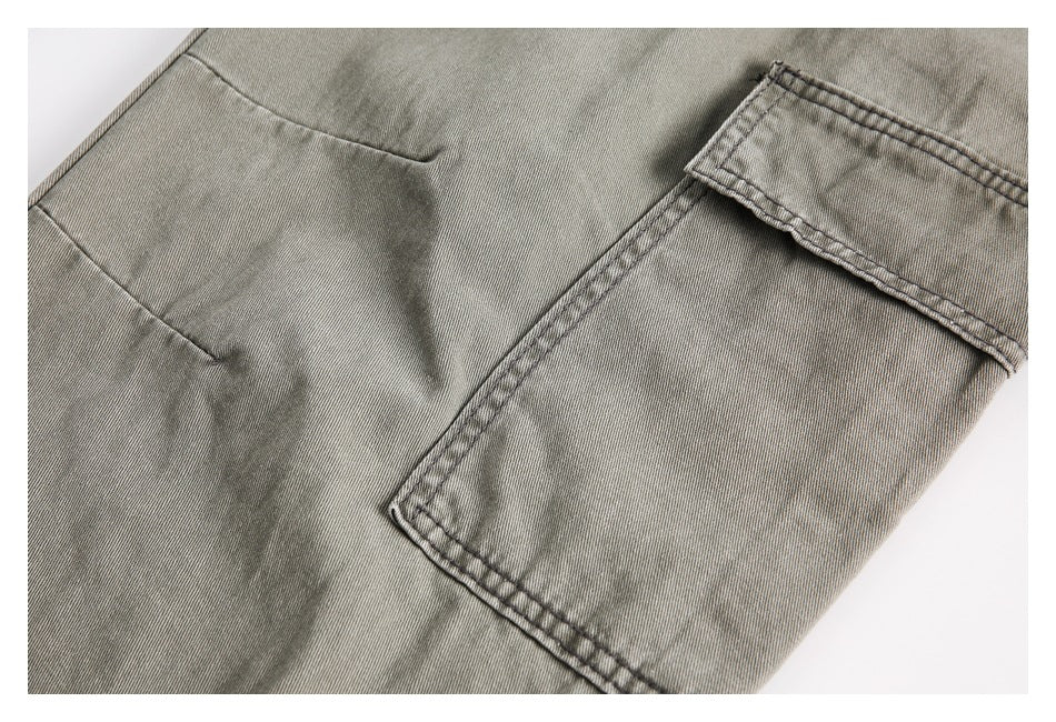 Close-up of a rectangular flap pocket on the side of gray-olive trousers.