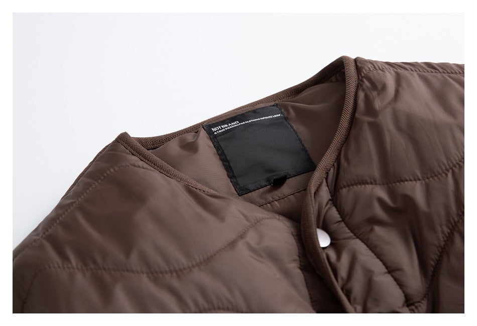 Close-up of a brown quilted jacket neckline, inner label, bound edge and white snap.