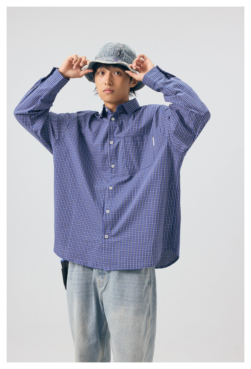 Model wearing a blue-and-yellow checked button-up shirt with a chest pocket, shown from the front.