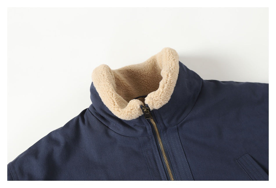 Cropped view of the navy jacket's front, showing its cream sherpa collar and brass zipper.