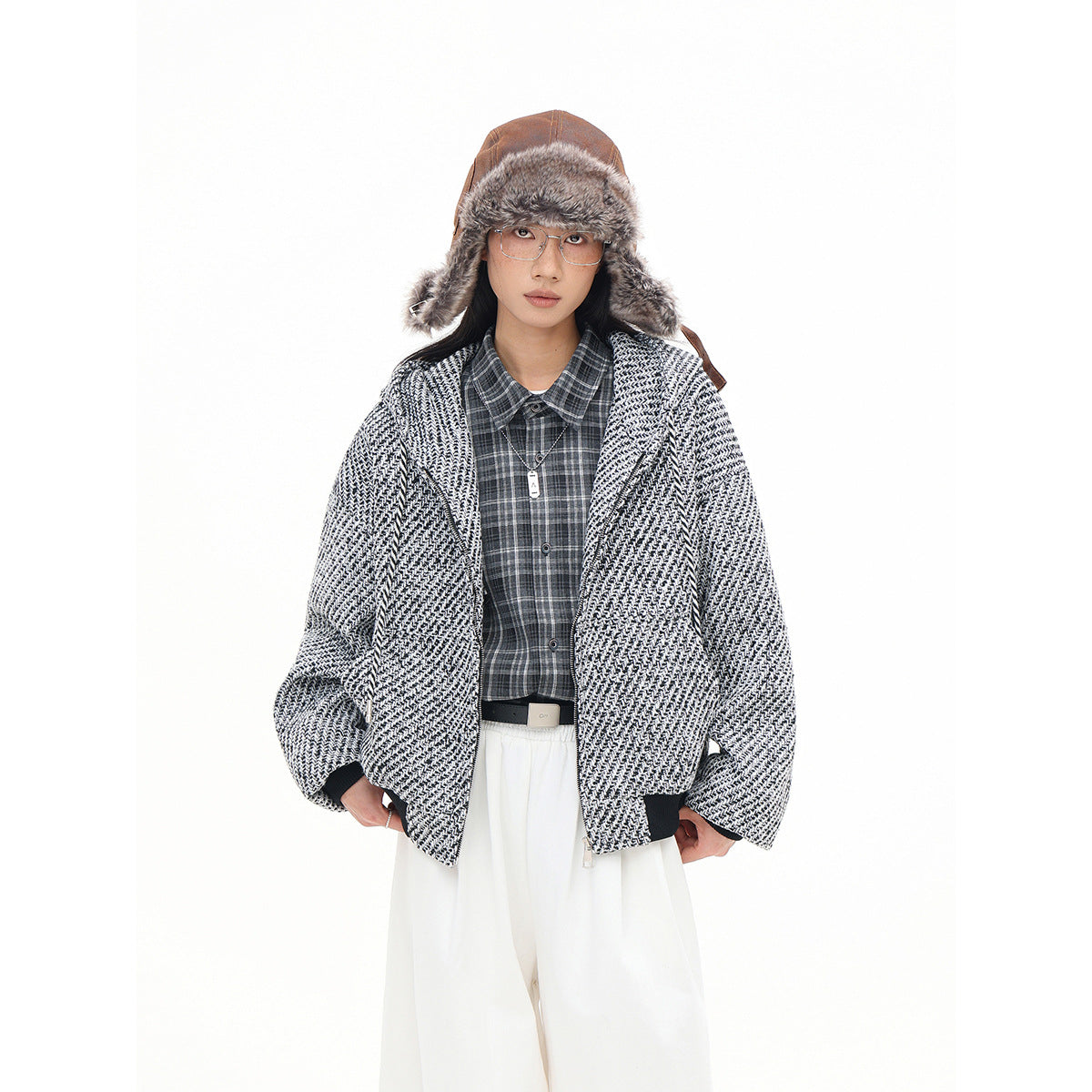 Closer front view of a model wearing an open black-and-white textured hooded jacket with dark cuffs.