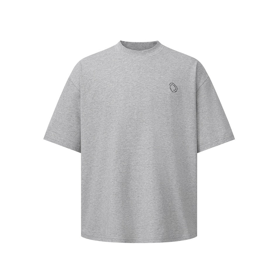 Front view of a heather gray oversized crew-neck T-shirt with a small dark circular chest emblem.
