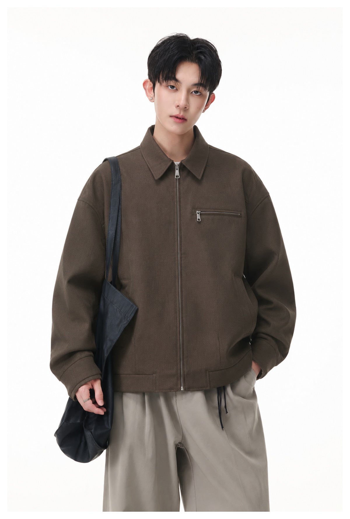 Model wearing a dark brown zip-front jacket with a pointed collar, chest zip pocket and side pockets.