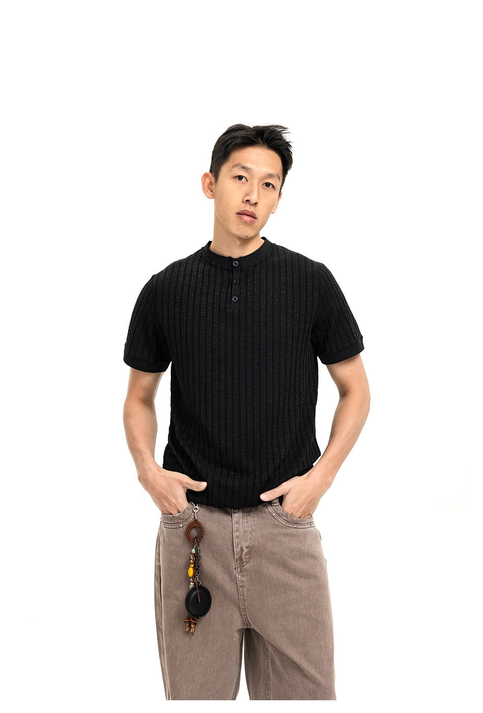 Front view of a model wearing a black ribbed henley and taupe jeans, cropped at the thighs.