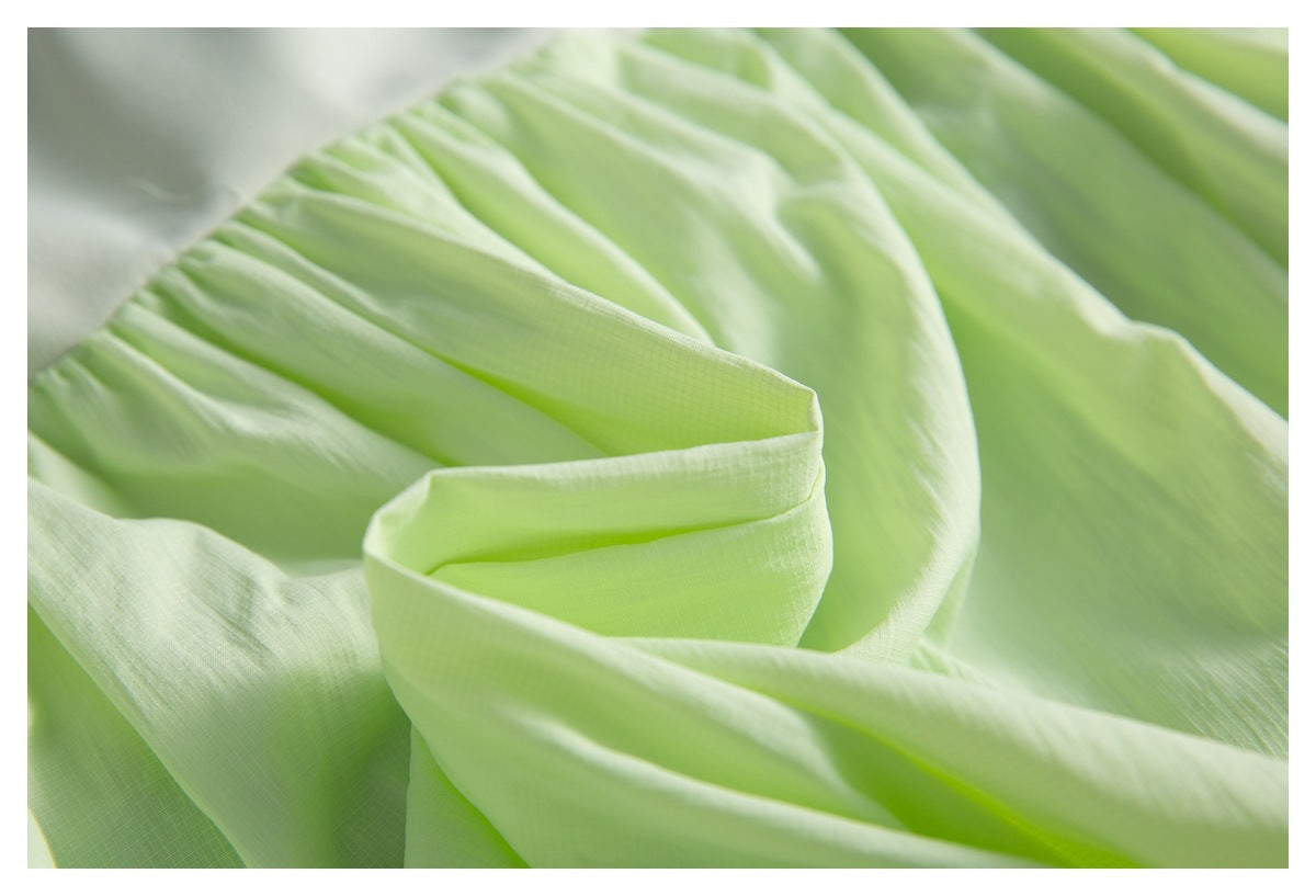Close-up of gathered, translucent light lime fabric in soft folds.