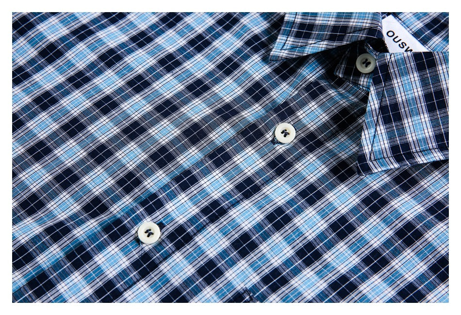 Close-up of a blue plaid shirt with its collar and several white buttons visible.
