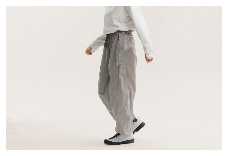 Cropped model in loose gray drawstring pants, shown from the side with a rear pocket visible.