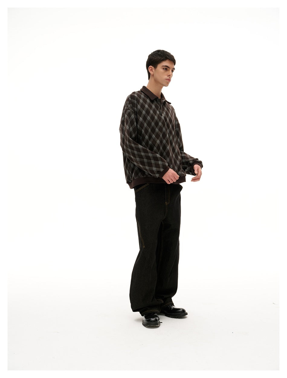Full-length view of a man in a brown diamond plaid polo sweatshirt, dark jeans and black shoes