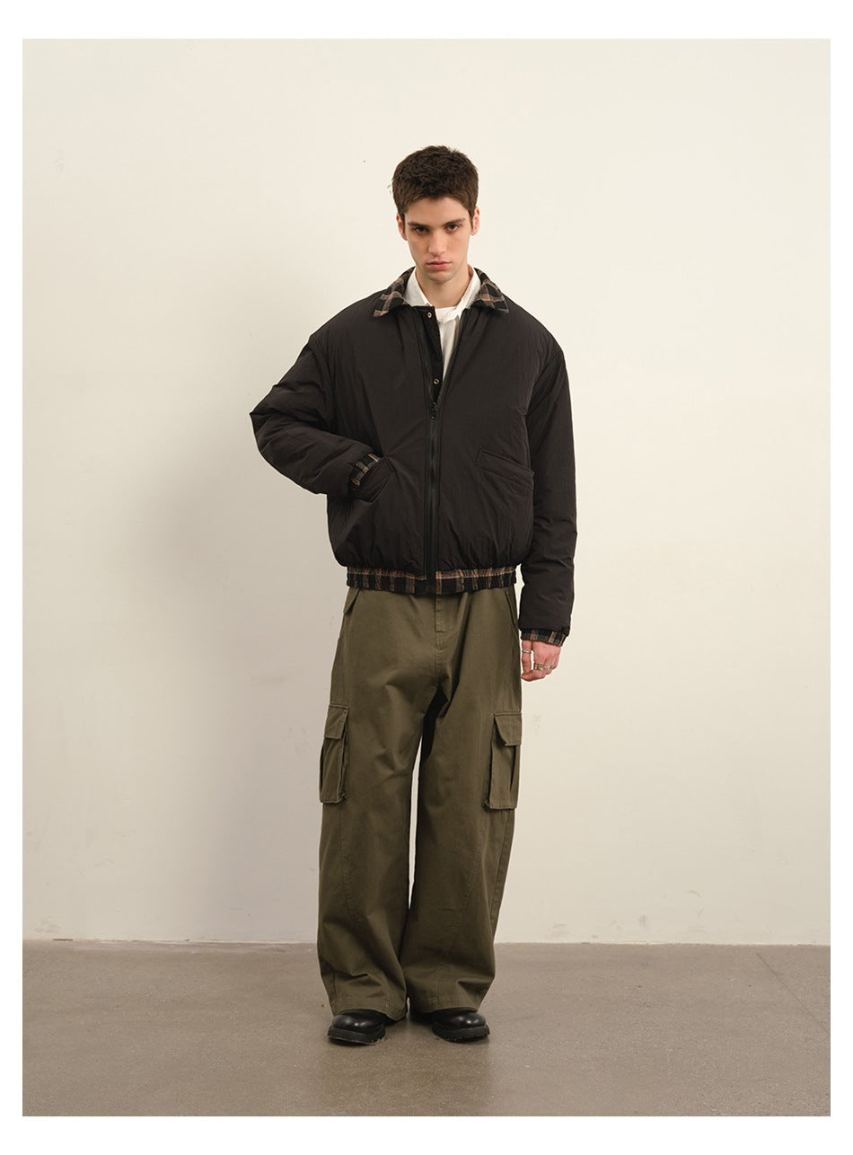 Model wearing a black zip jacket with plaid trim and loose olive cargo trousers.