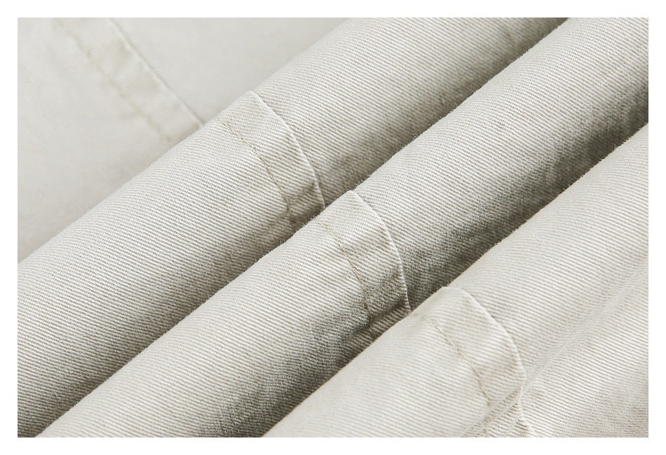 Close-up of cream fabric with diagonal twill texture and stitched seams.