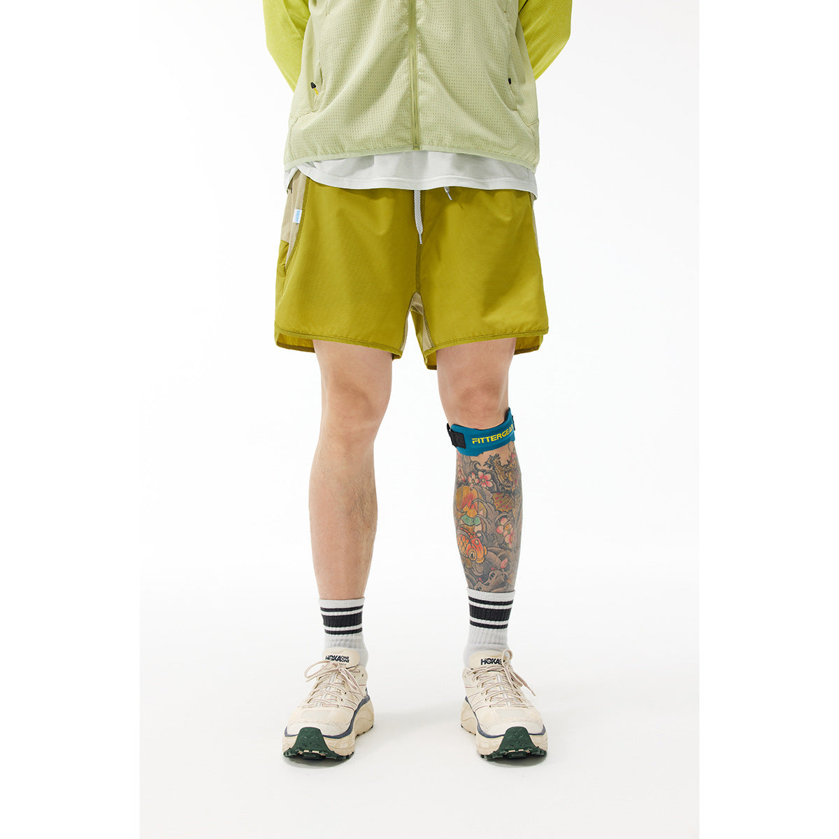 Model wearing golden olive running shorts with a drawstring and side pockets, shown from the waist down.