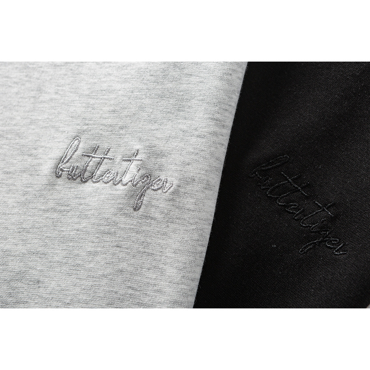 Close-up of cursive embroidery on light gray and black knit fabric.