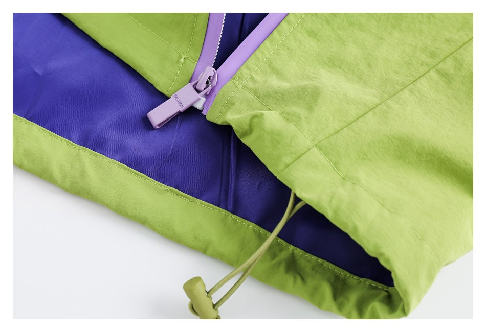 Close-up of a lavender zipper, purple lining, and lime-green drawcord toggle on a jacket.