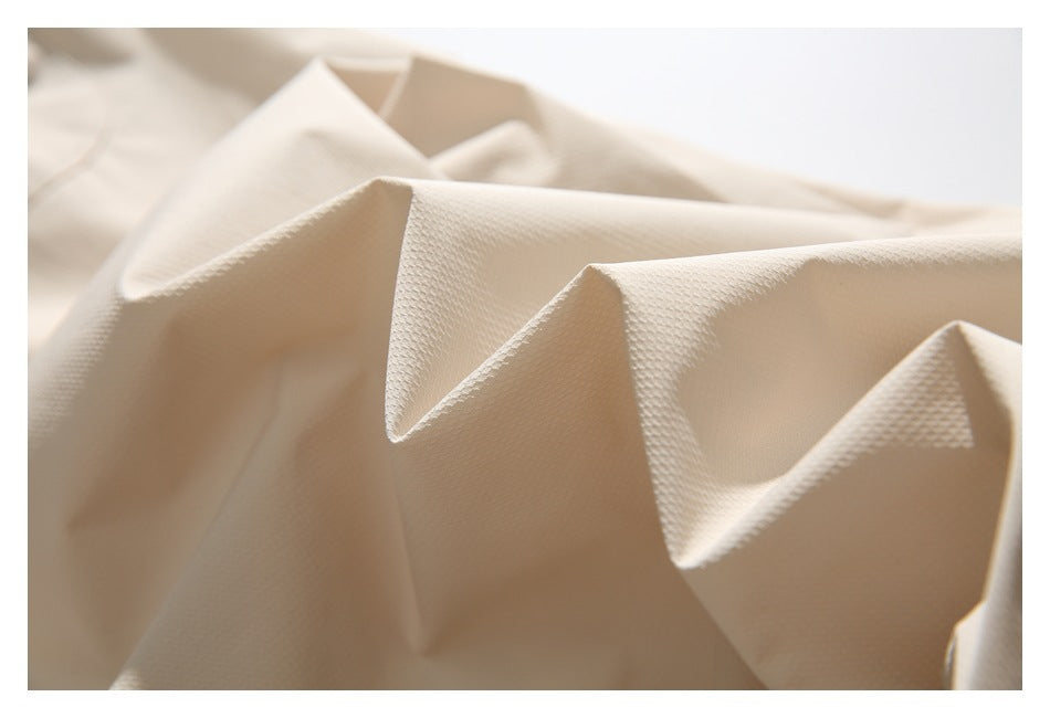 Close-up of cream-colored textured fabric arranged in soft folds.