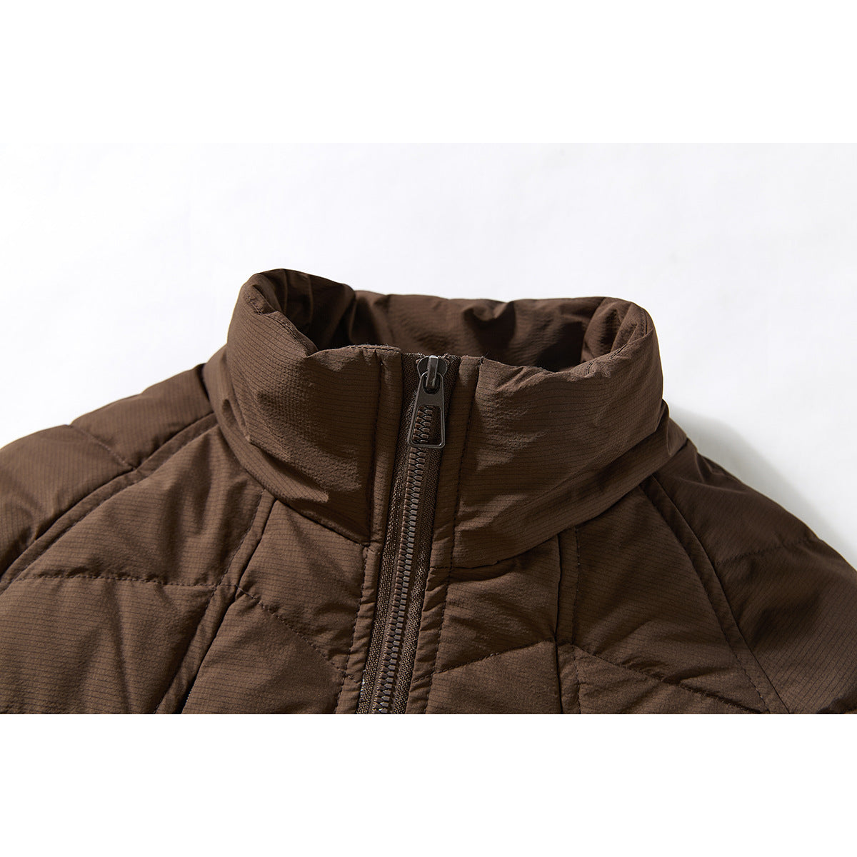 Close-up of a brown quilted jacket’s raised collar and central front zipper.