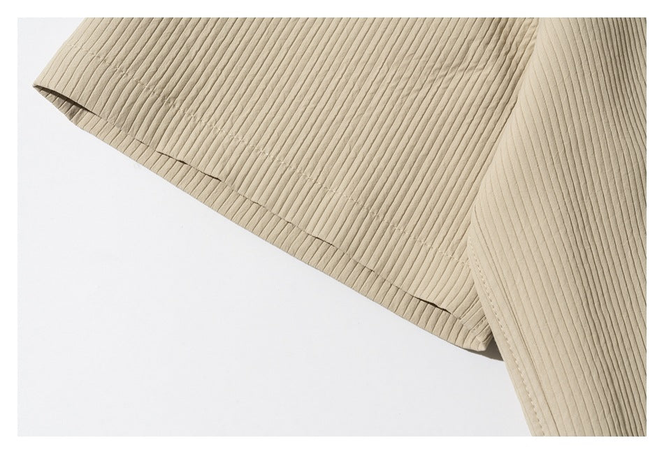 Close-up of the short sleeve and stitched hem on a beige ribbed shirt.