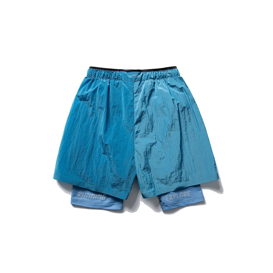 Back view of shiny teal-blue layered shorts with RUNNING and EXPLORE lettering on the inner shorts.