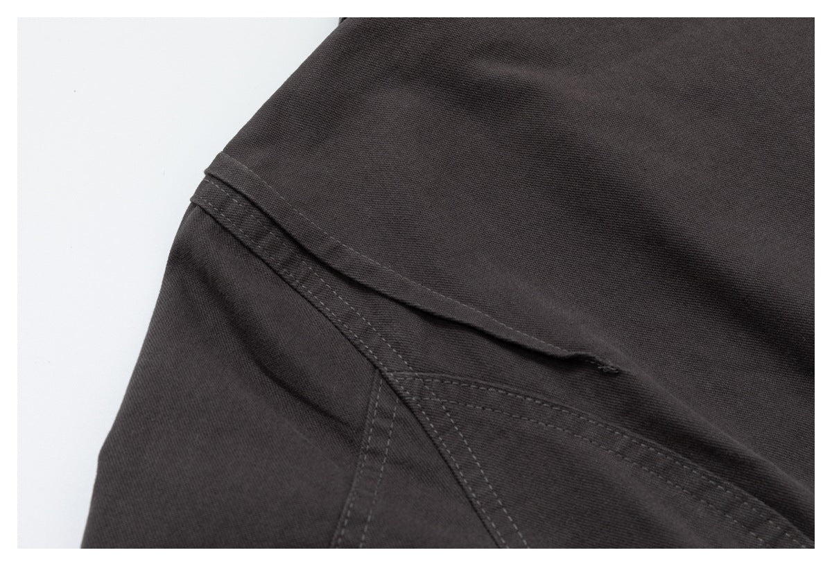 Close-up of a dark charcoal jacket seam with layered fabric and parallel stitching.