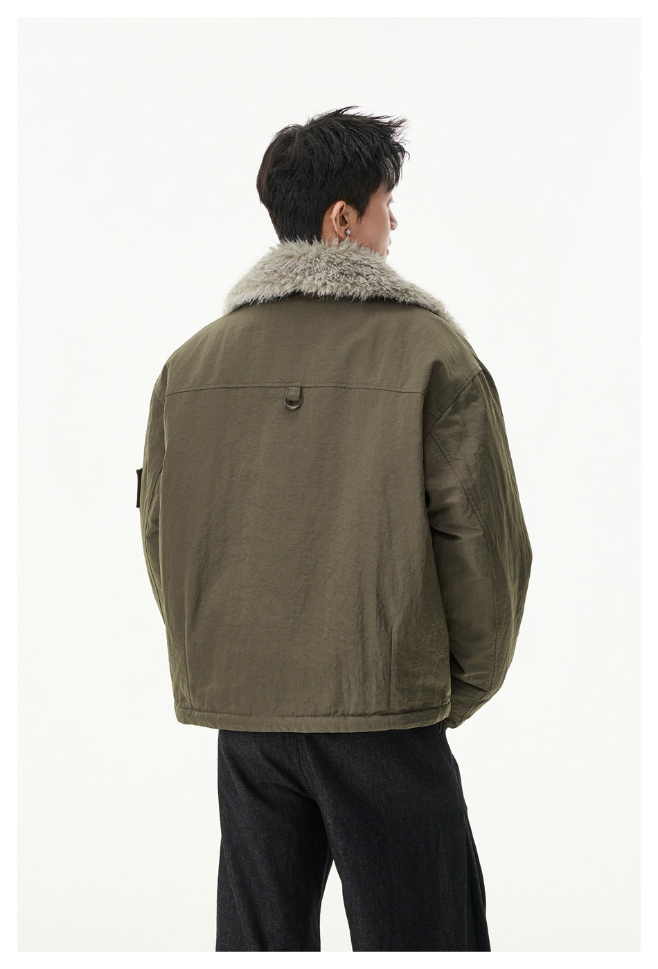 Rear view of a model wearing the olive jacket, showing its plush collar and plain back with a small D-ring.