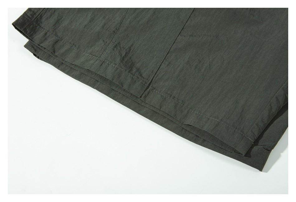 Close-up of the dark olive garment's layered hem and stitching.