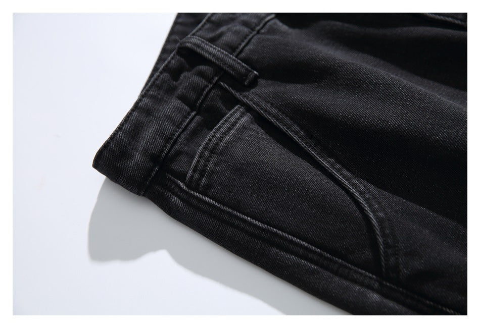 Close-up of black jeans showing a belt loop, curved pocket seam and double stitching.