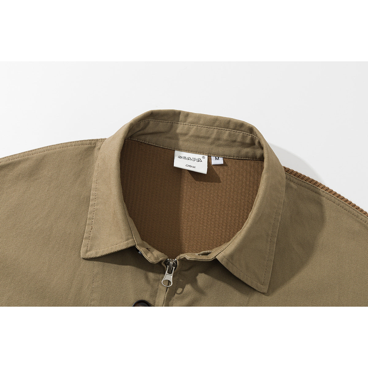 Close-up of a tan jacket’s pointed collar, front zipper, and sewn-in neck label.