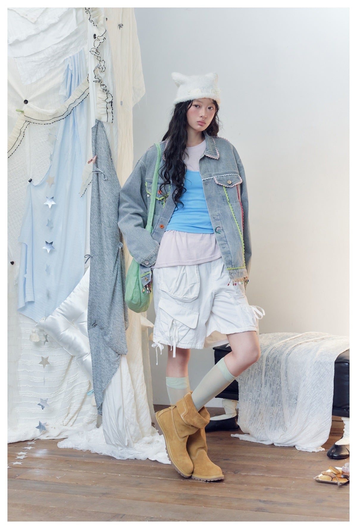 Model wearing an embellished light-wash denim jacket with a blue top and white cargo shorts.