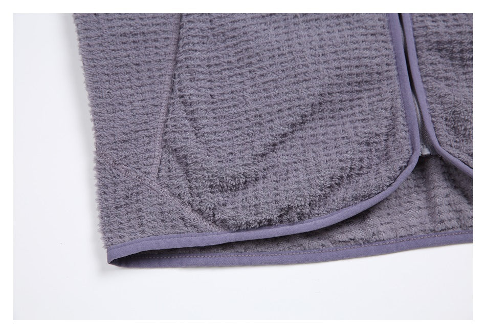 Close-up of a rounded pocket corner and bound hem on a gray textured garment.