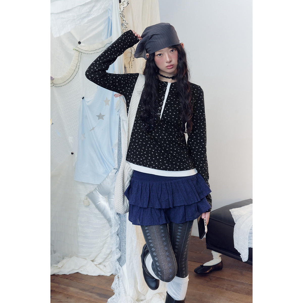 Model wearing a black patterned long-sleeve top, navy tiered skirt and patterned tights.
