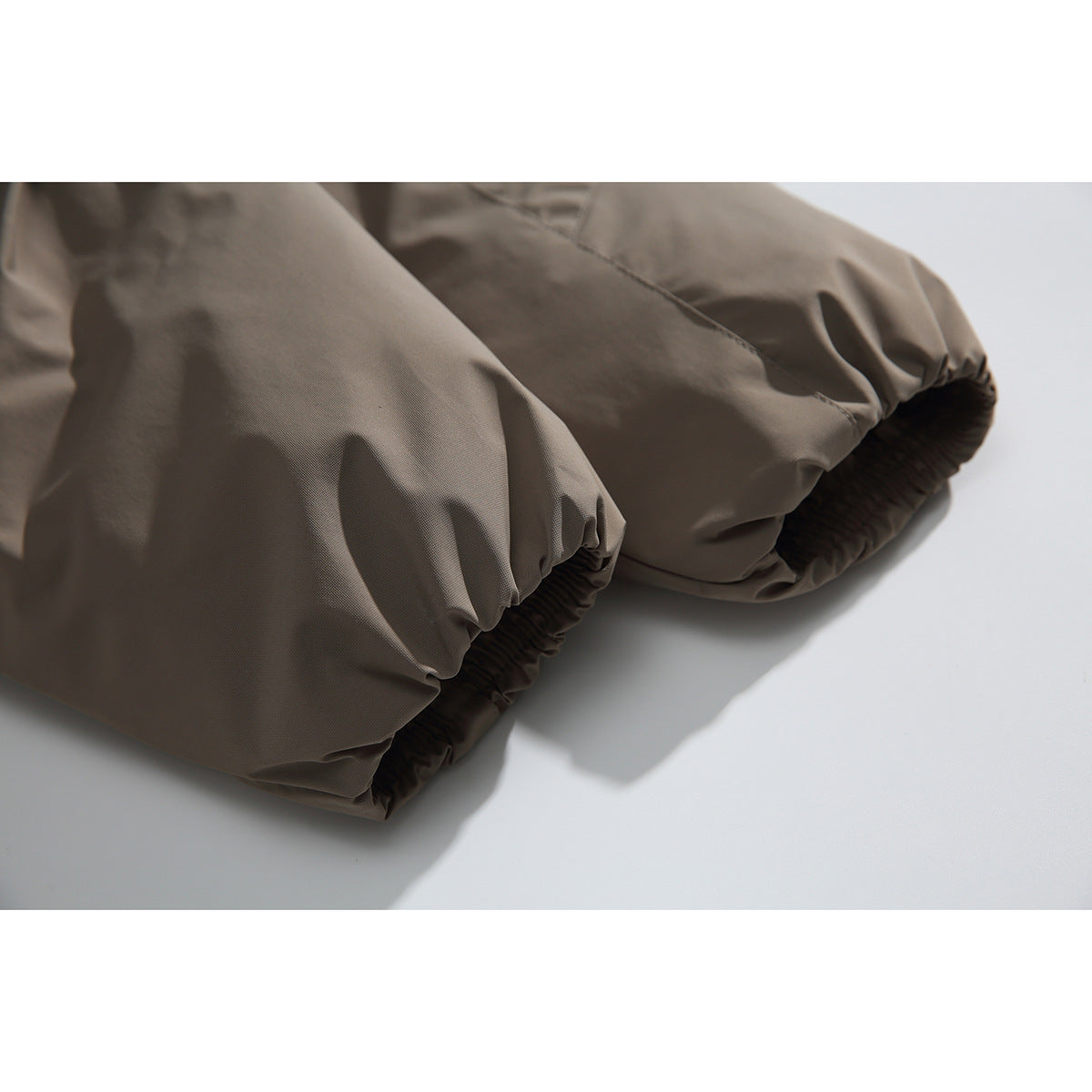 Close-up of the taupe jacket's gathered elastic cuffs and stitched sleeve seams.