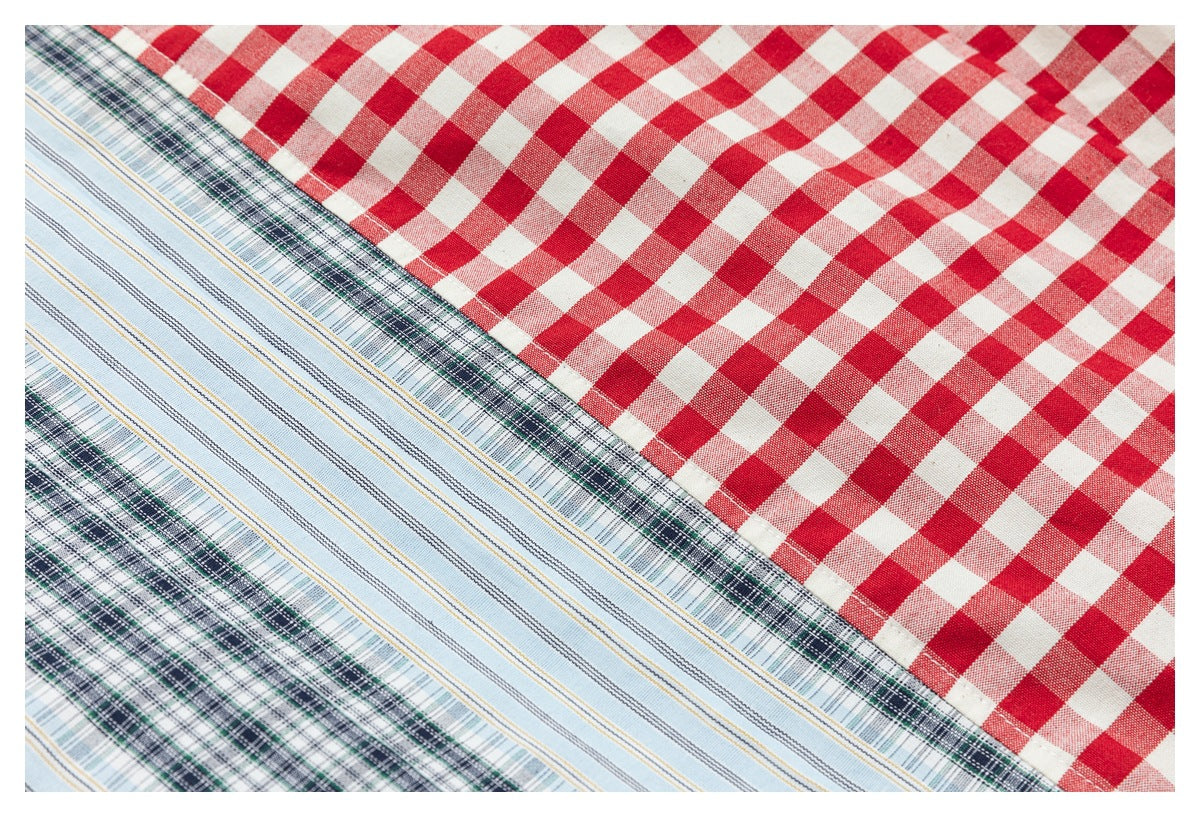 Close-up of fabric panels joining: red-and-white gingham, pale blue stripes, and dark green plaid.