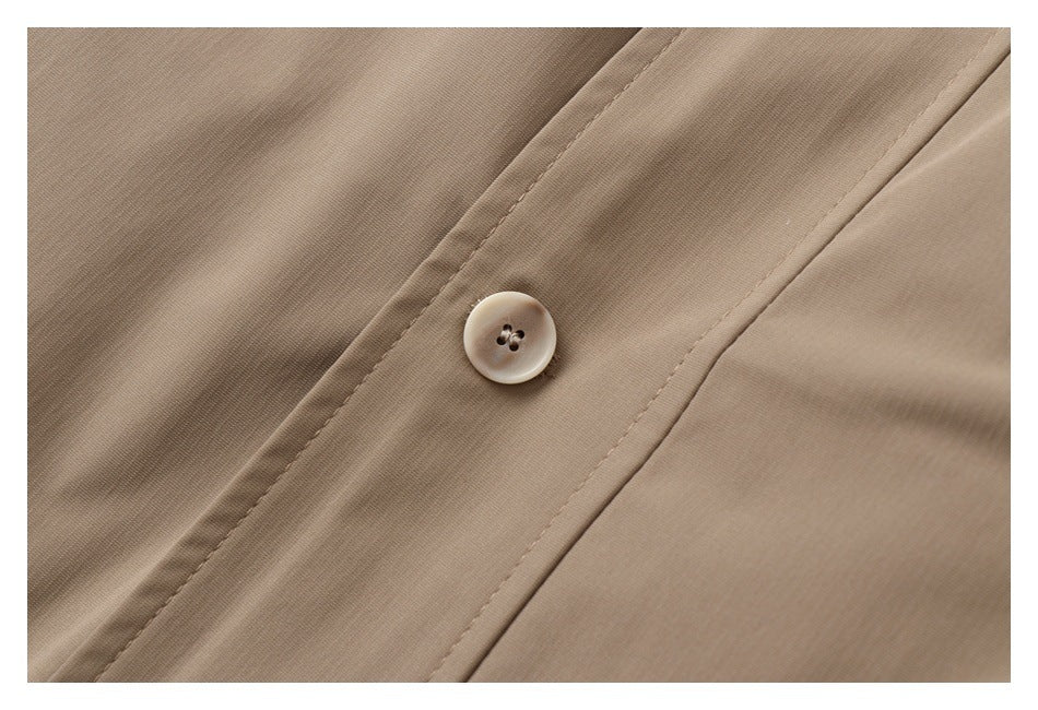Close-up of a tan coat button on a stitched front placket.