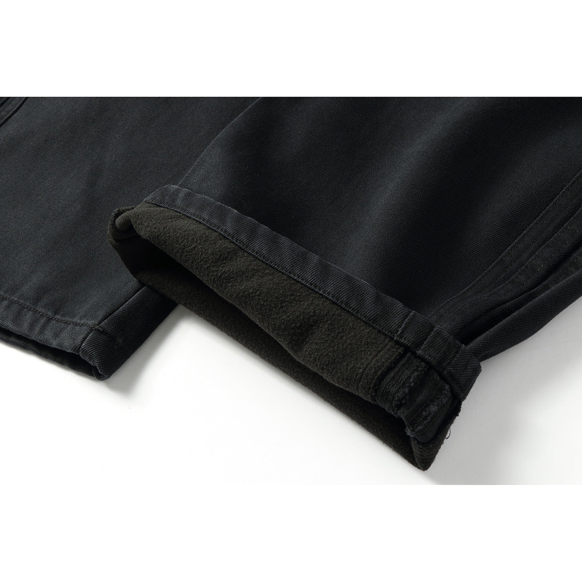 Close-up of a black pants leg hem folded back to show its dark, fuzzy inner lining.