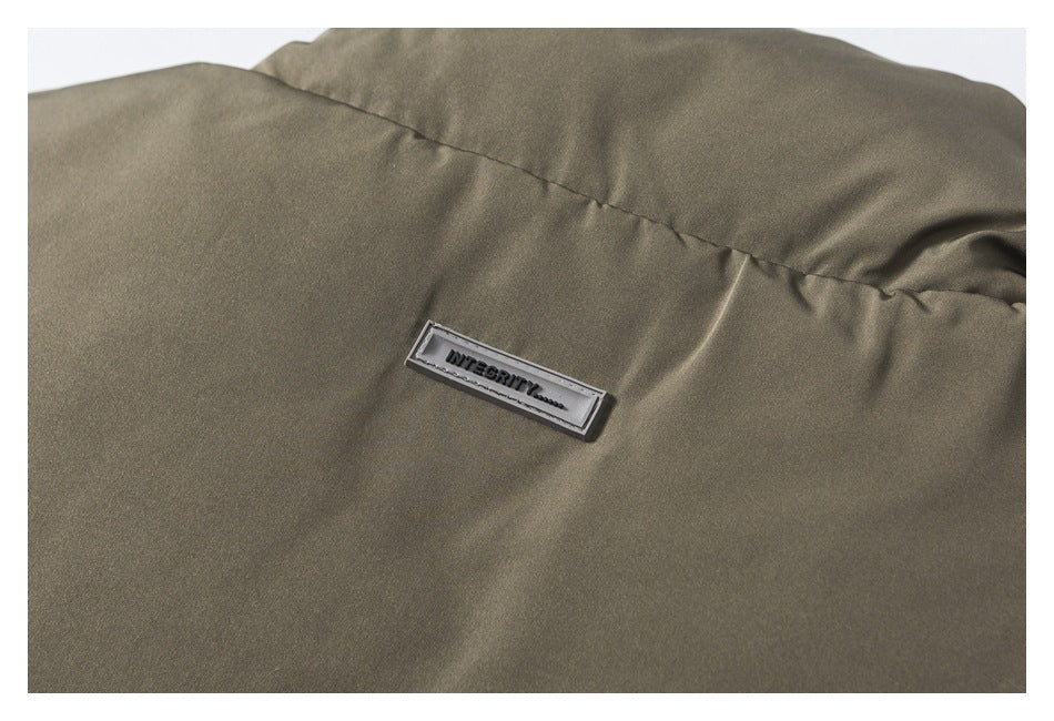 Close-up of olive-gray garment fabric with a seam and a small rectangular stitched label.