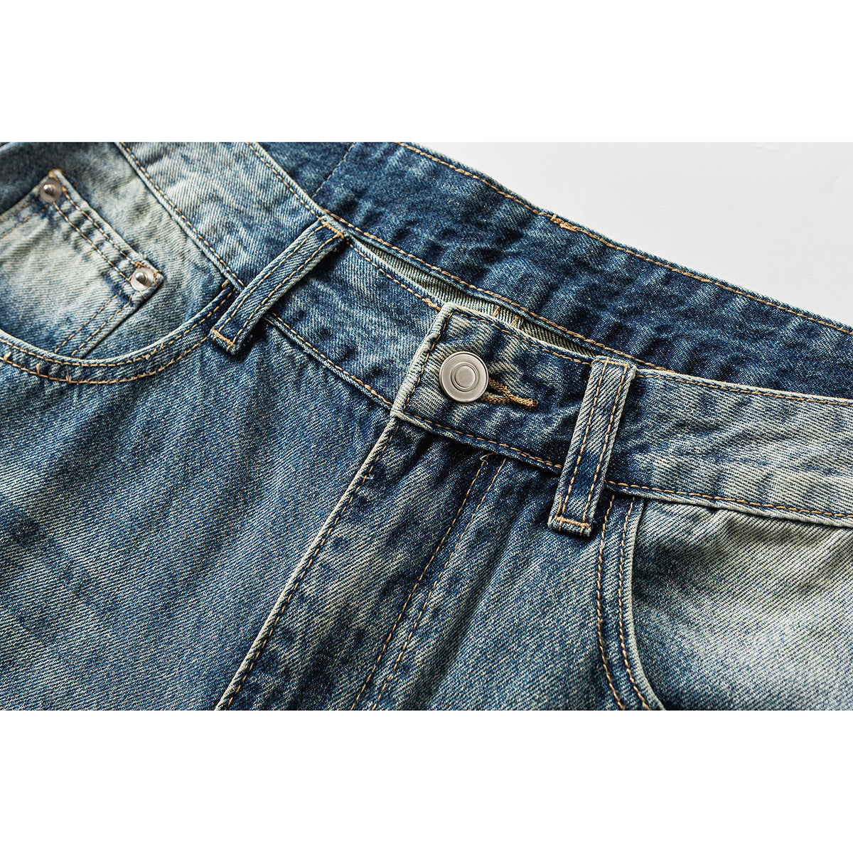 Close-up of faded blue jeans showing the waistband button, belt loops, fly stitching, and front coin pocket.
