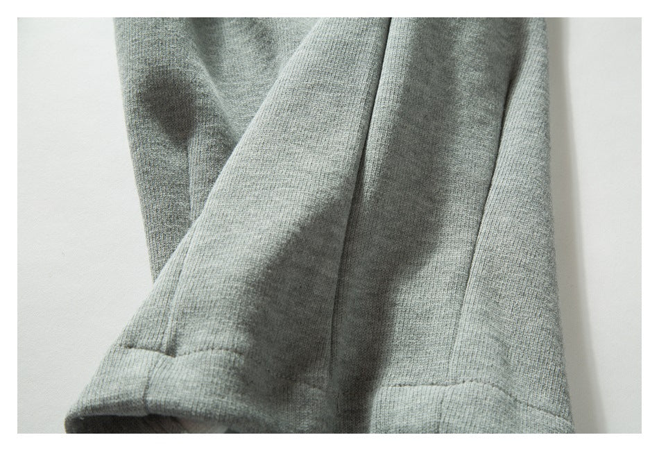 Close-up of the folded hem and stitched seams of a light gray knit garment.
