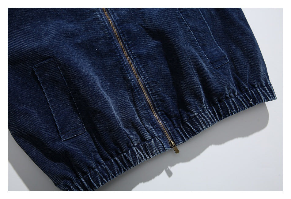 Cropped front view of a navy corduroy jacket showing its zipper, two pockets, and elasticated hem.