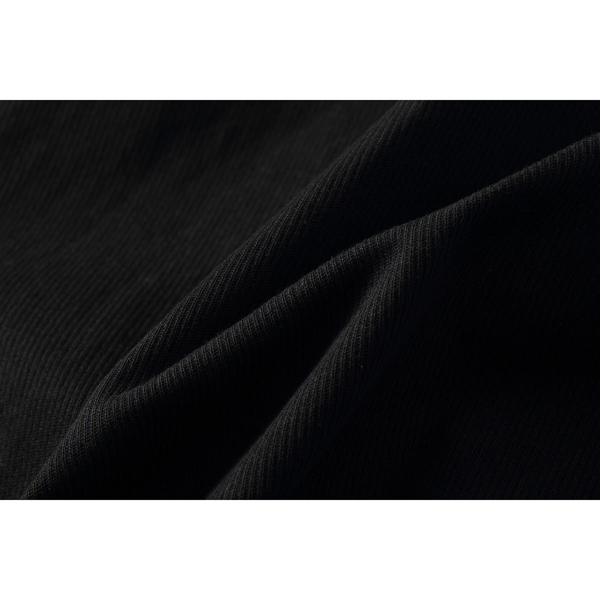 Macro view of black trouser fabric folded to show its fine ribbed texture.
