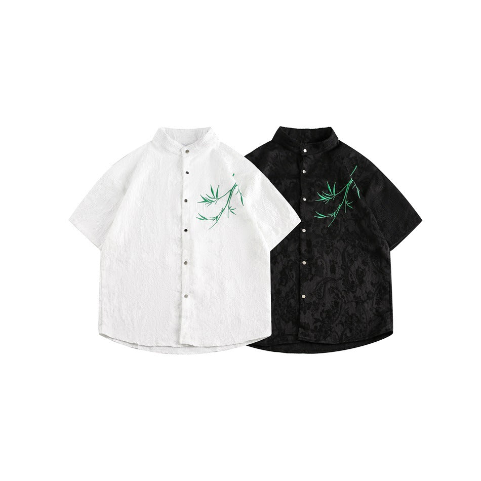 White and black short-sleeve mandarin-collar shirts with snap buttons and green bamboo embroidery.