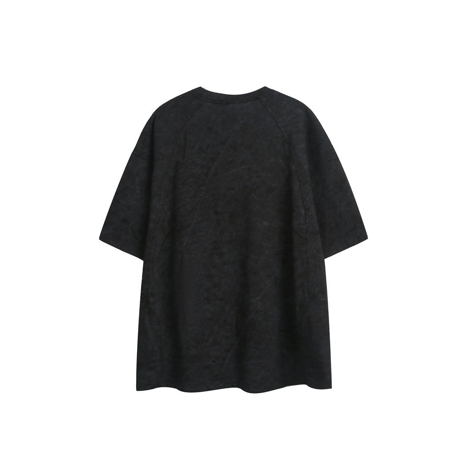 Back view of a loose black short-sleeve crewneck T-shirt with subtle mottled distressing.