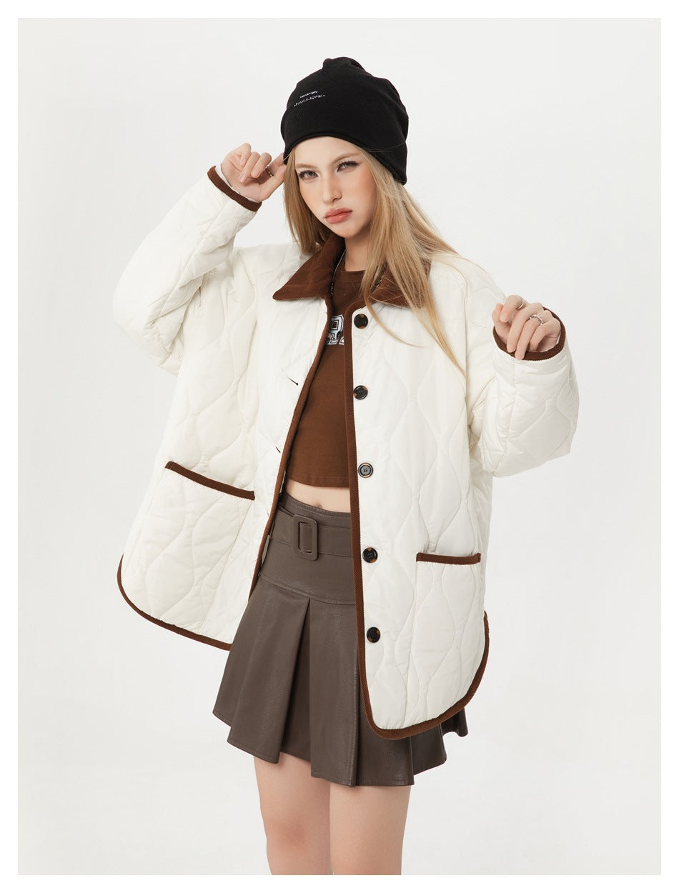 Model wearing an open ivory quilted jacket with brown trim, showing its front pockets and button closure.