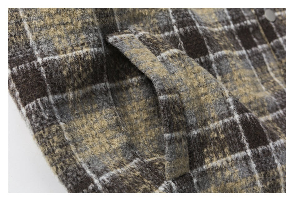 Close-up of a plaid jacket pocket flap and snap on brown, charcoal and tan fabric.